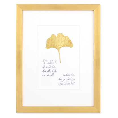 Goldenes Glück - Vergoldetes Ginkgoblatt mit Spruch. Glücklich ist nicht der, der alles hat was er will, sondern der der zu schätzen weiß was er hat. Poetisches Spruchbild mit Massivholzrahmen.