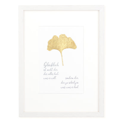 Goldenes Glück - Vergoldetes Ginkgoblatt mit Spruch. Glücklich ist nicht der, der alles hat was er will, sondern der der zu schätzen weiß was er hat. Poetisches Spruchbild mit Massivholzrahmen.